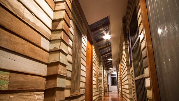 A narrow hallway with wooden paneling and a sloped ceiling. - Here Hostel (Bangkok)