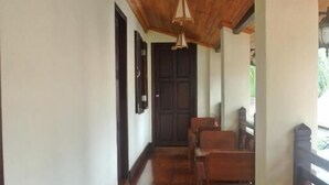 Un pasillo con suelo y techo de madera, que conduce a una puerta oscura.