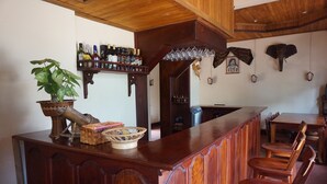 Una zona de bar con mobiliario de madera, una planta en maceta y una variedad de botellas.