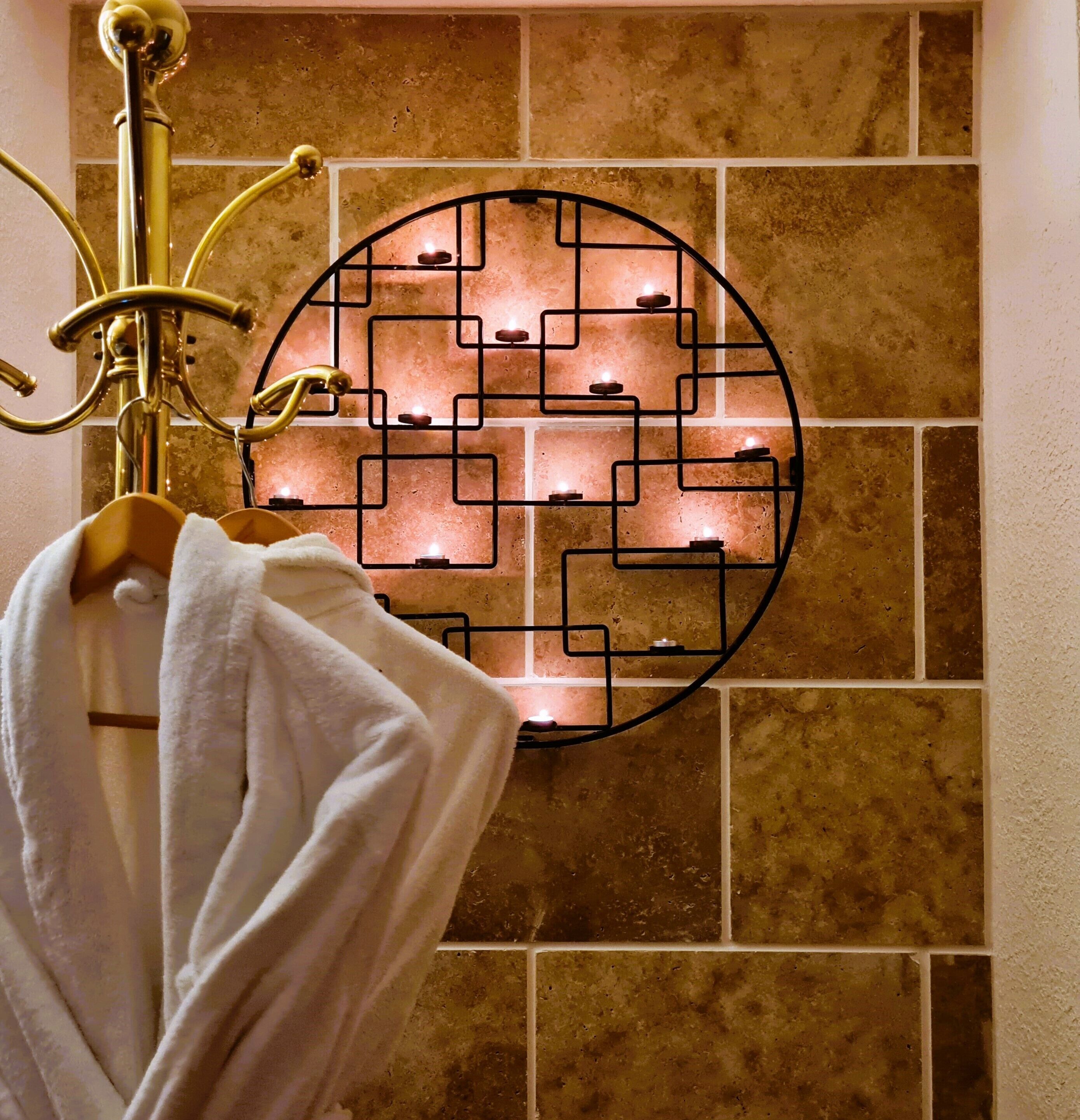 A bathroom with a towel rack, a decorative wall piece, and a gold-colored showerhead.