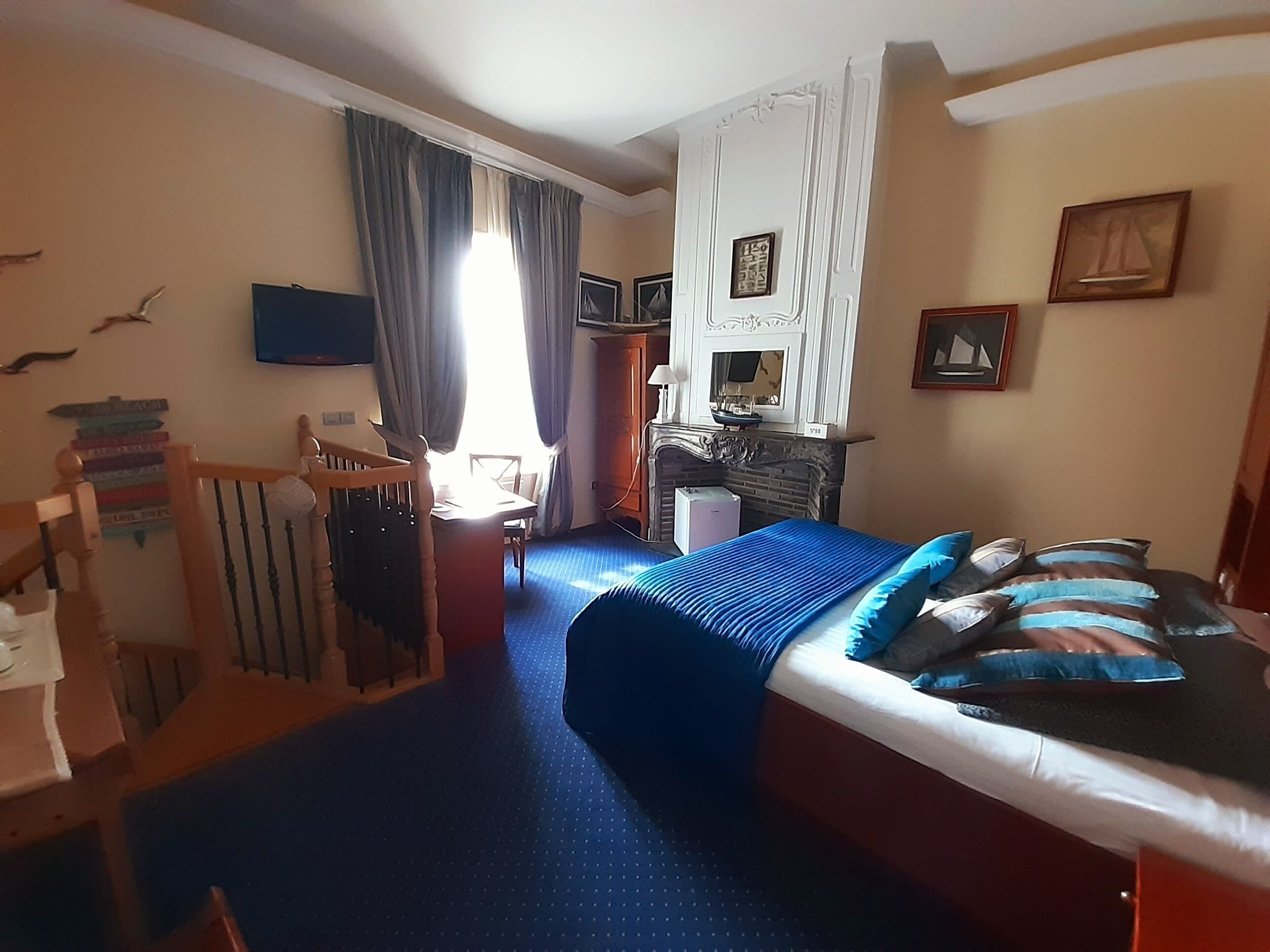 A bedroom with a bed, a desk, a chair, a dresser, and a window with curtains.
