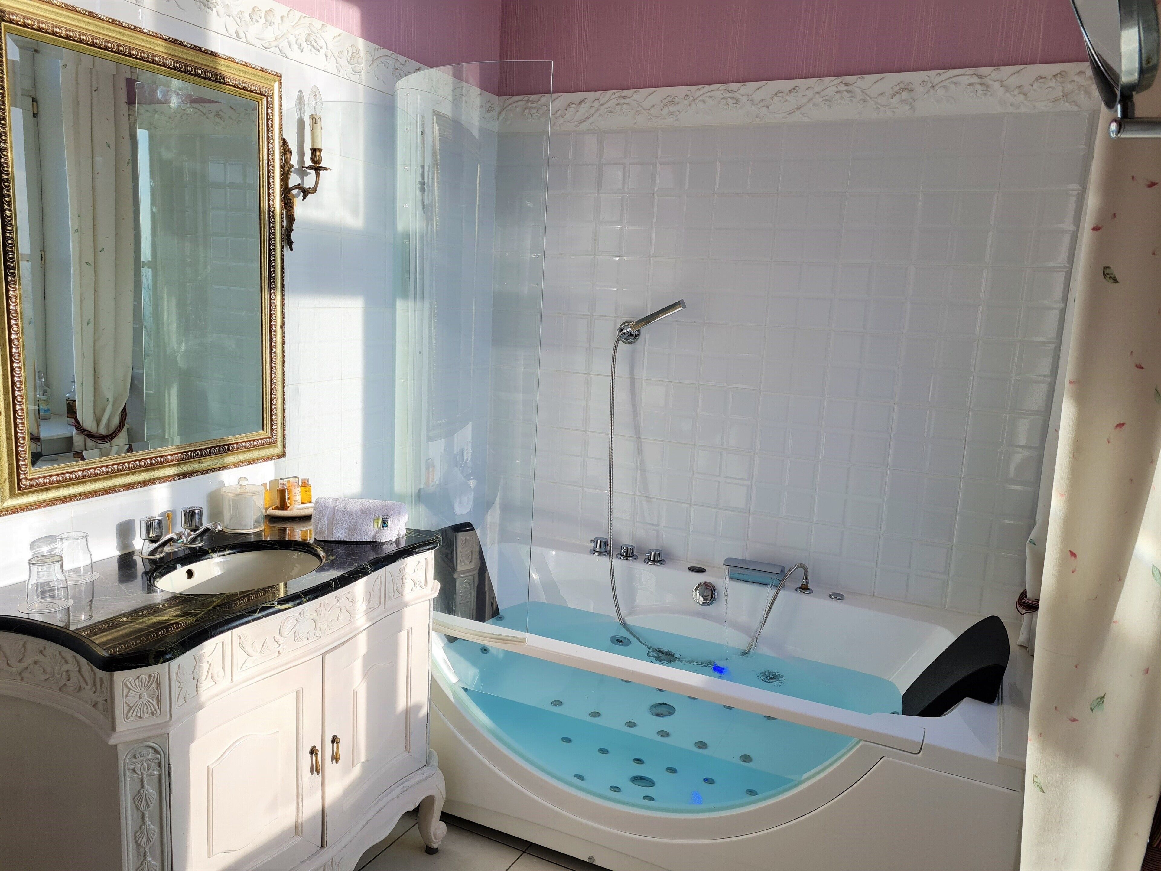 A bathroom with a white vanity, a large mirror, a bathtub, and a shower.