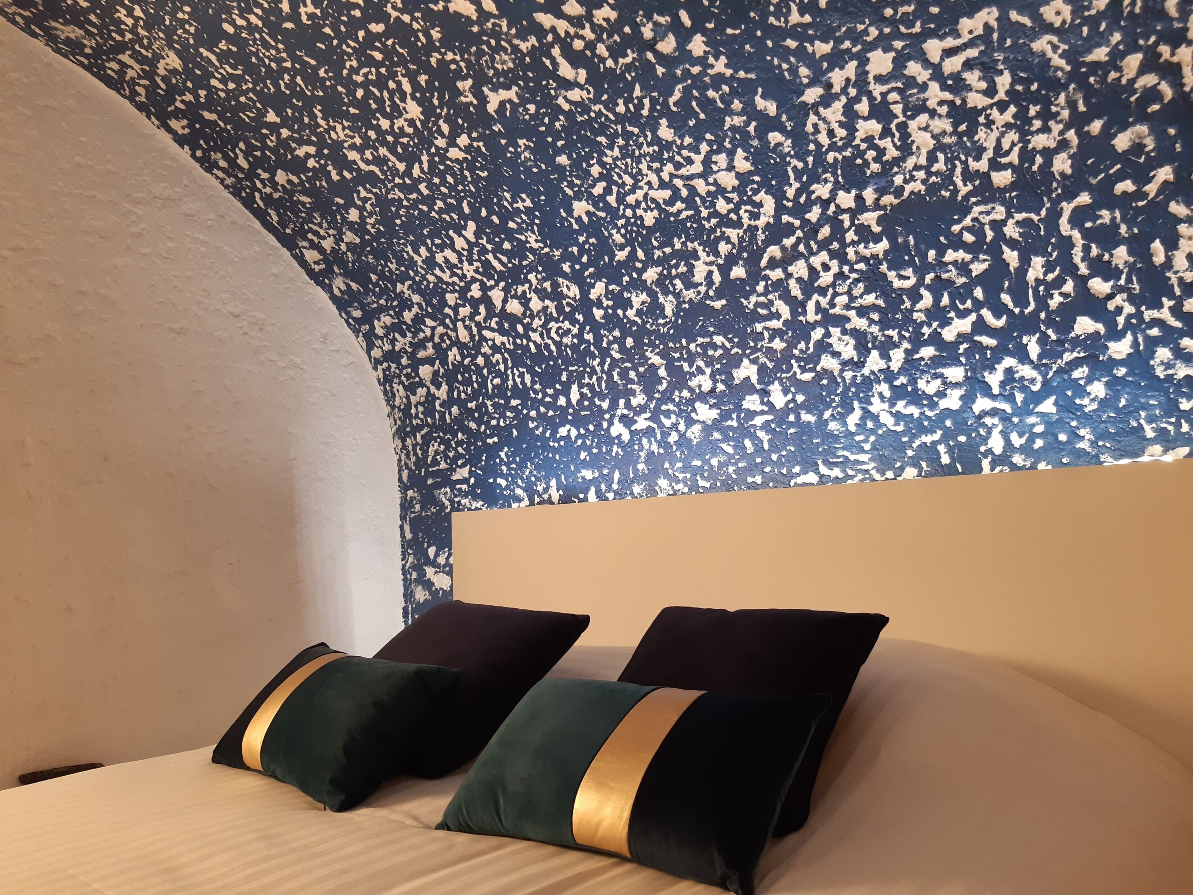 Quarto com teto arredondado e cama com duas almofadas.