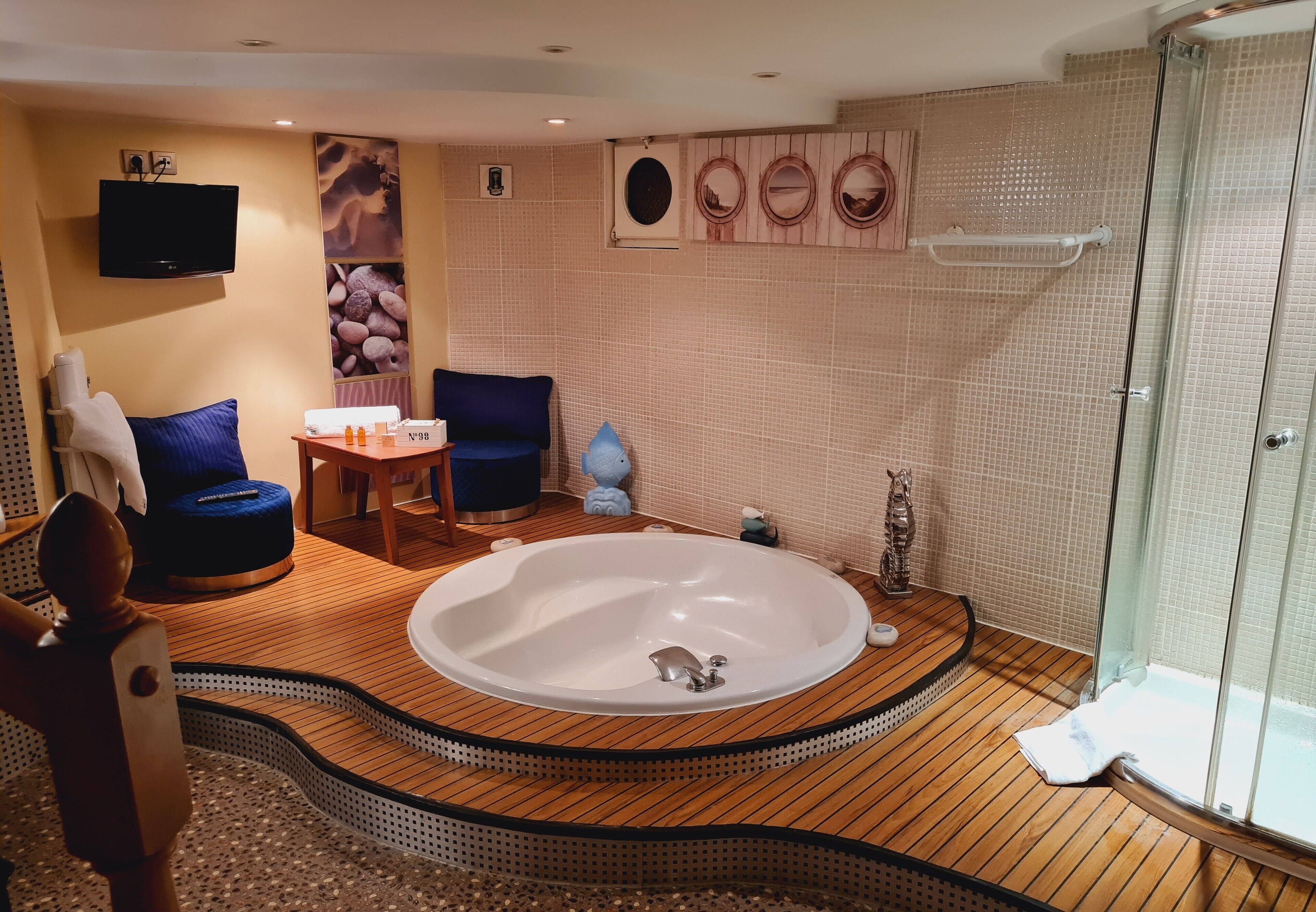 A modern bathroom with a freestanding bathtub, a glass-enclosed shower, and a wooden floor.