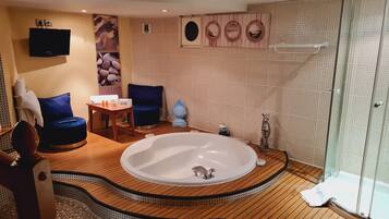 A modern bathroom with a freestanding bathtub, a glass-enclosed shower, and a wooden floor.