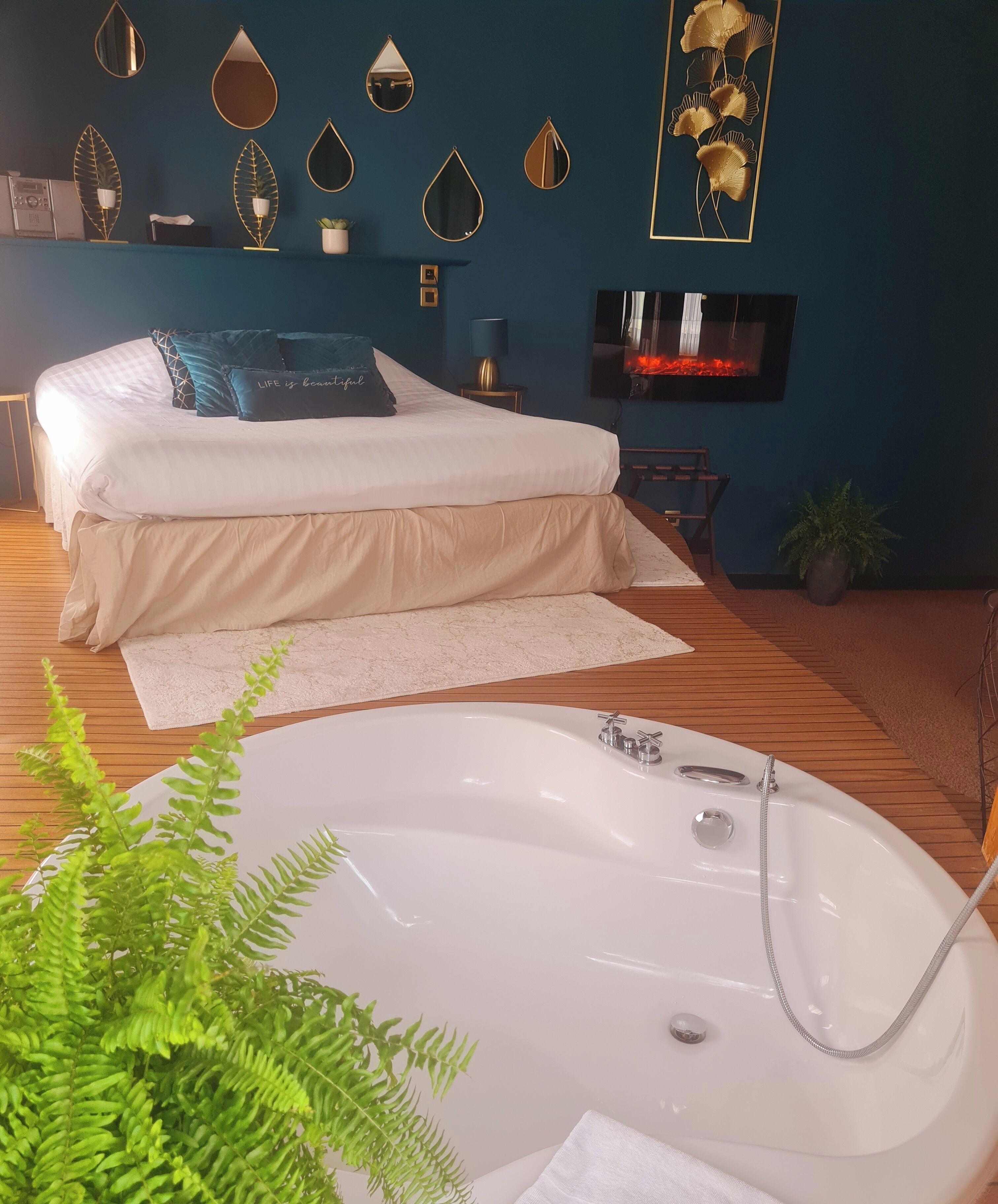 Quarto com cama grande, mesa de cabeceira, televisão na parede e uma banheira grande.