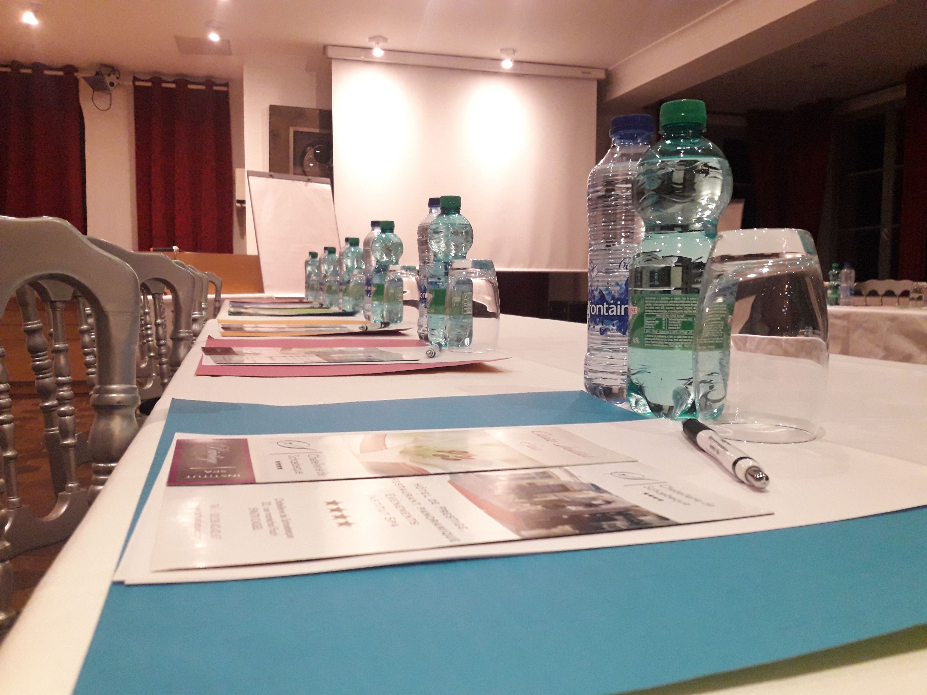 Une table de conférence avec des bouteilles d’eau, des documents et un stylo.