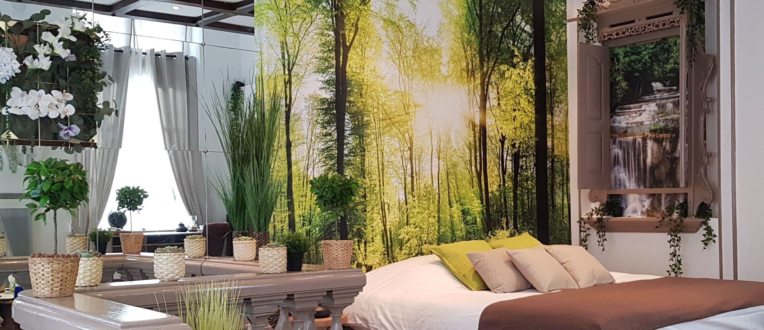 Un dormitorio con cama, ventana grande y pared decorada con un mural de un bosque.