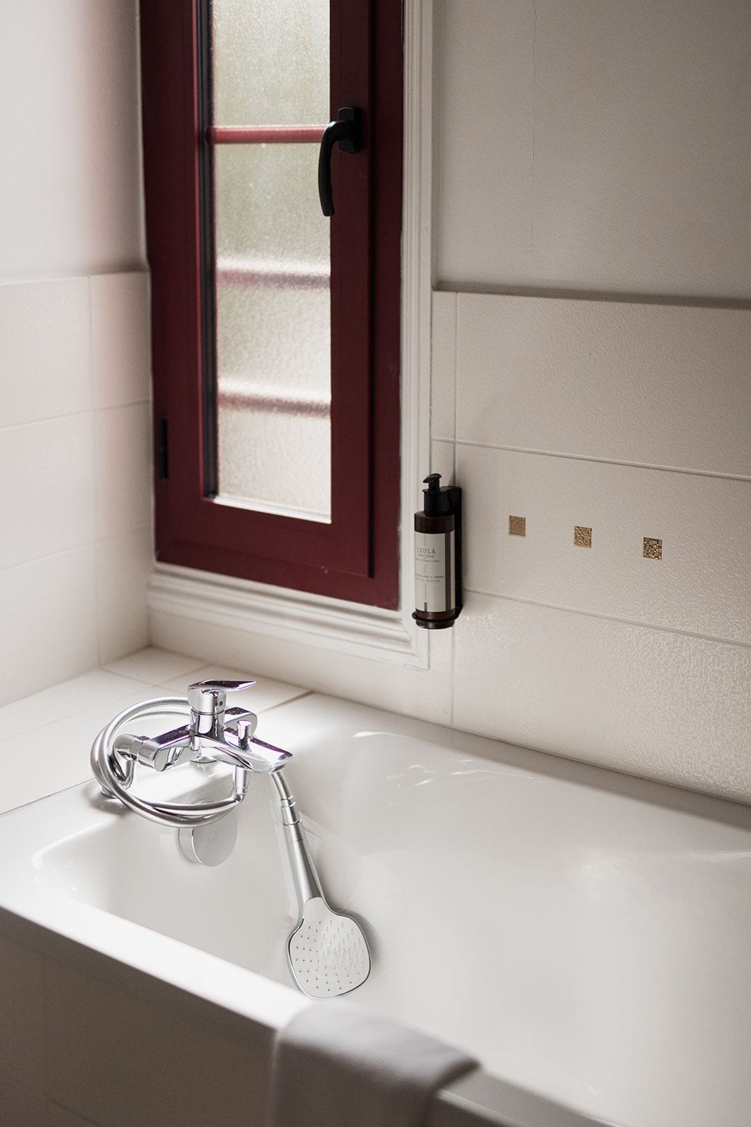 A bathroom with a white bathtub, a chrome faucet, and a handheld showerhead.