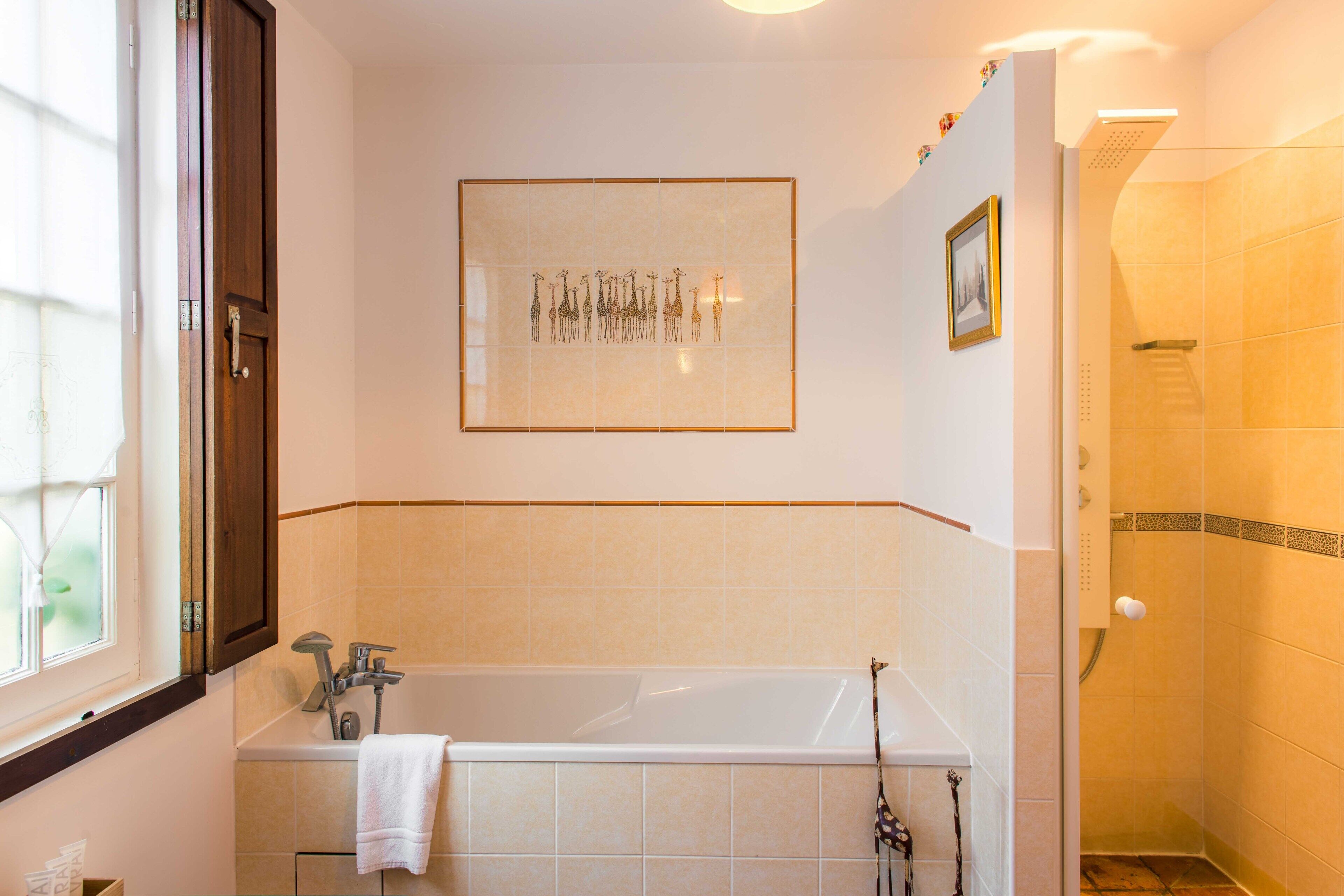 A bathroom with a bathtub, a shower, and a framed artwork on the wall.