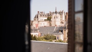Une vue par la fenêtre sur un ensemble de bâtiments historiques comprenant plusieurs structures, dont une tour imposante.