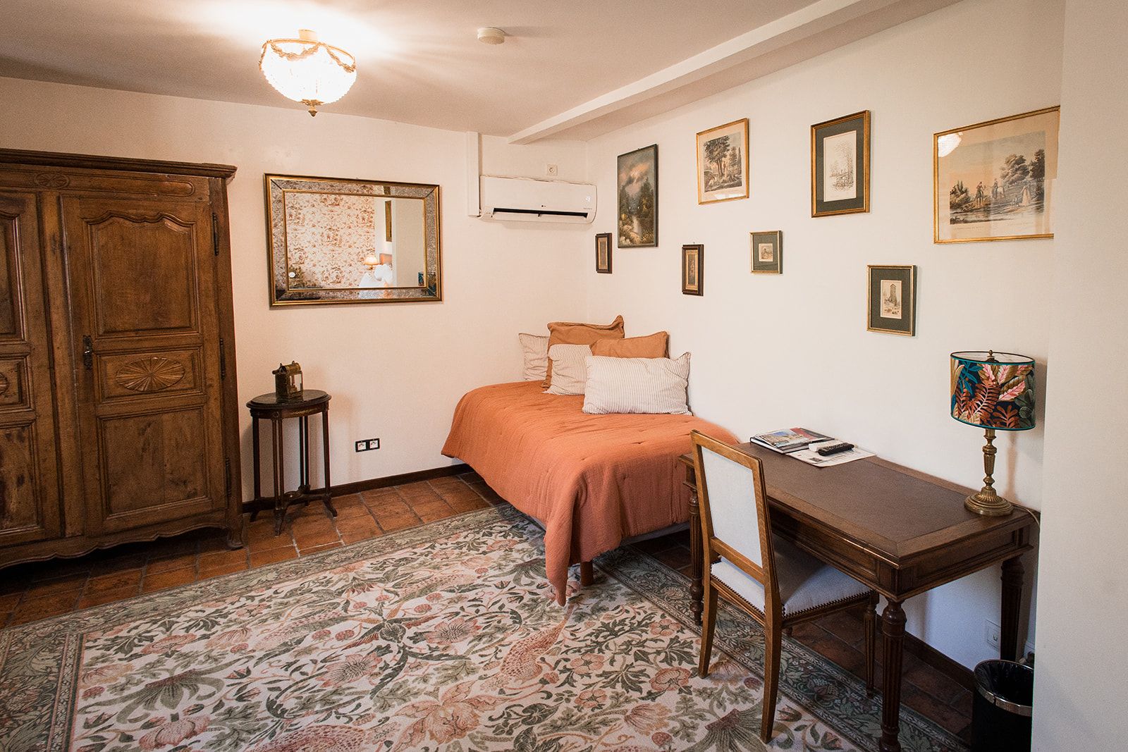 Une chambre à coucher comprenant un lit, un bureau, une chaise, une armoire et un miroir.
