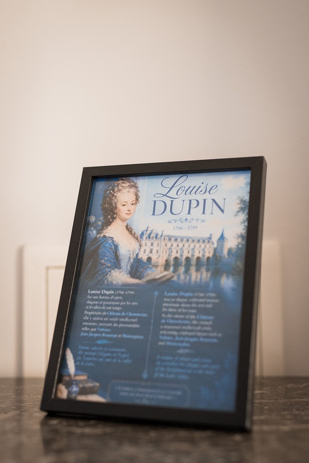 Un portrait encadré de Louise Dupin, avec un bâtiment historique en arrière-plan.