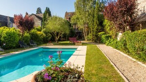 Une piscine dotée d’une terrasse dallée, entourée de pelouse et de haies bien entretenues.