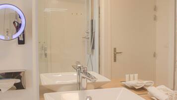 A modern bathroom with two sinks, a mirror, and a shower.