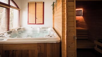 A wooden cabin with a hot tub, wooden walls, and a window with blinds.