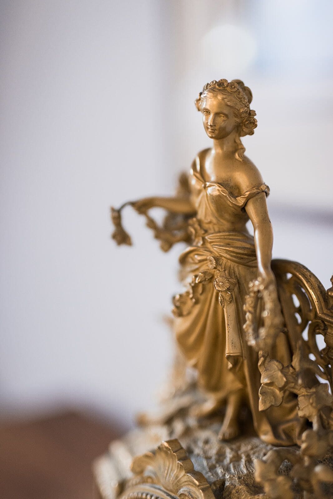 A golden statue of a woman with intricate details, standing on a decorative base.