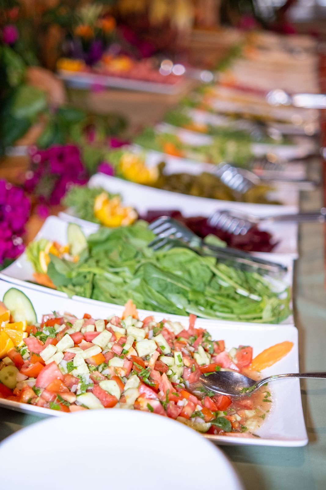 A buffet table with various food options including salads, fruits, and vegetables.