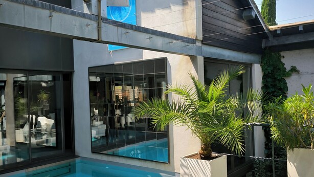 A modern outdoor pool area with glass flooring, white lounge chairs, and potted plants. - Be Loft B&B Pool & Spa (Avignon)