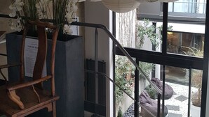 A staircase with a wooden chair, a potted plant with white flowers, and hanging paper lanterns. - Be Loft B&B Pool & Spa (Avignon)