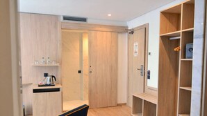 A modern hotel room with a wooden floor, a blue sofa, a wooden wardrobe, and a small kitchenette area. - Rihab Hotel (Rabat)