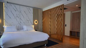 A modern bedroom with a large bed, marble-patterned wall, wooden panel divider, and a wooden bench. - Rihab Hotel (Rabat)