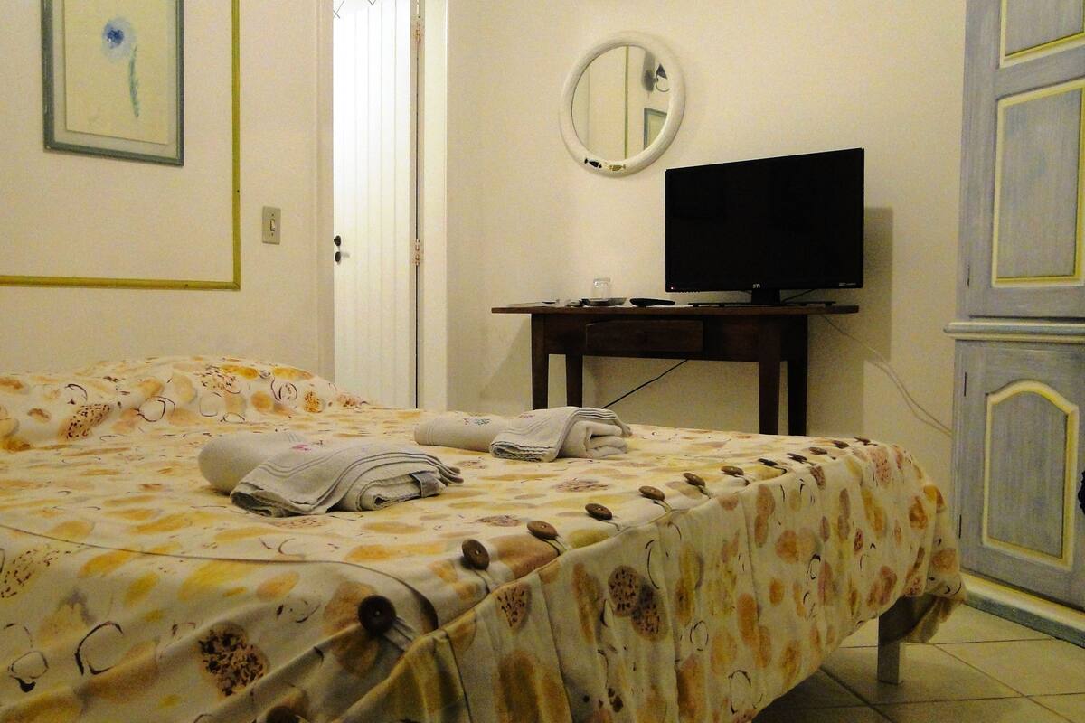Ein Hotelzimmer mit Bett, Fernseher auf einem Schrank, Spiegel an der Wand und Kleiderschrank.