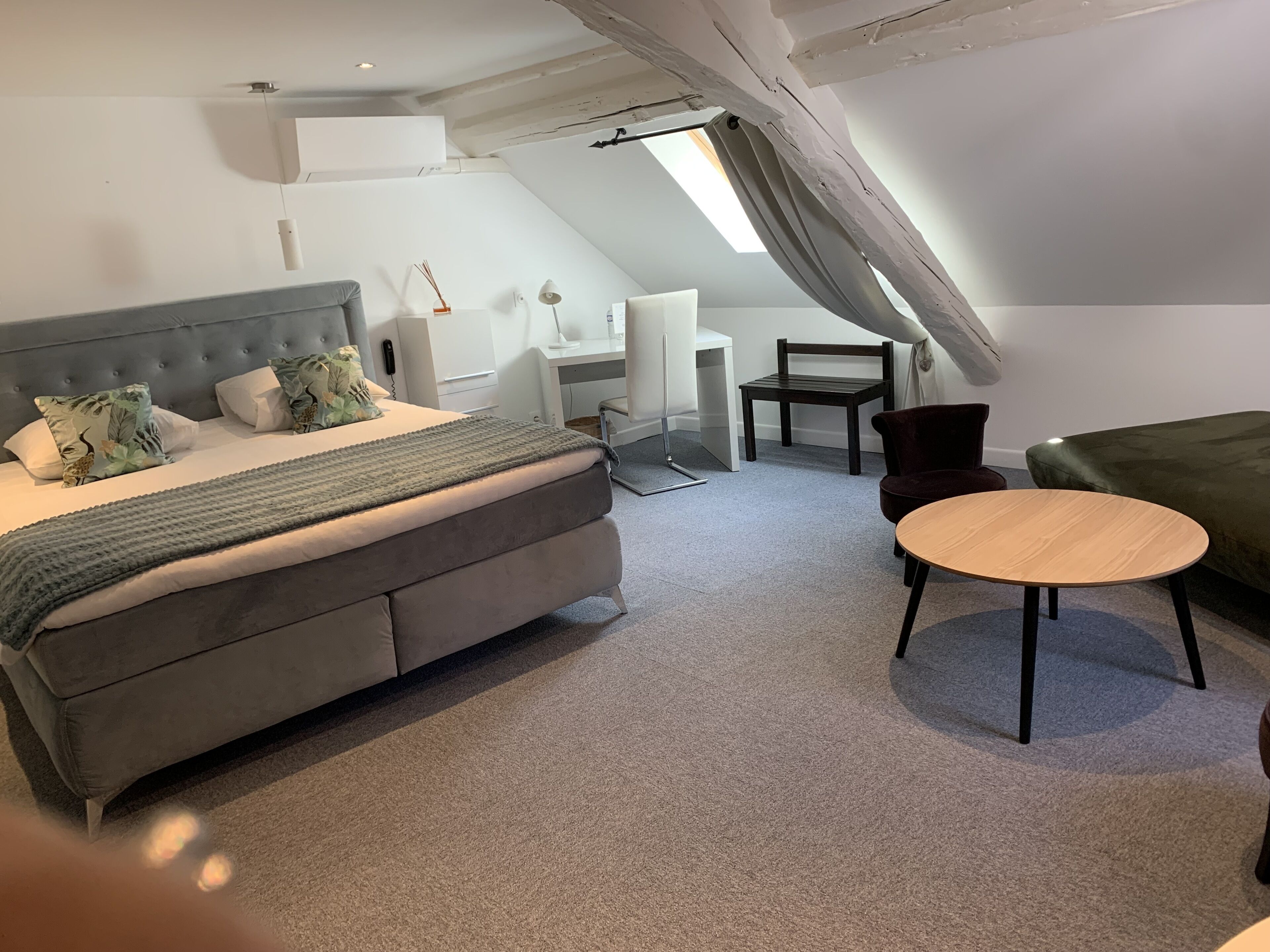 A modern loft bedroom with a large bed, a desk, and a chair.