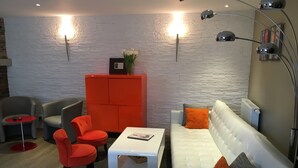 A modern living room with a white sofa, red chairs, a small white table, and a red cabinet. - Au Cheval Blanc Hôtel et Restaurant (Ribeauvillé)