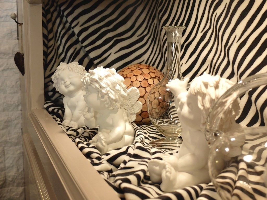 Um arranjo decorativo com tecido estampado em padrão de zebra, um vaso de vidro e uma esfera de madeira.
