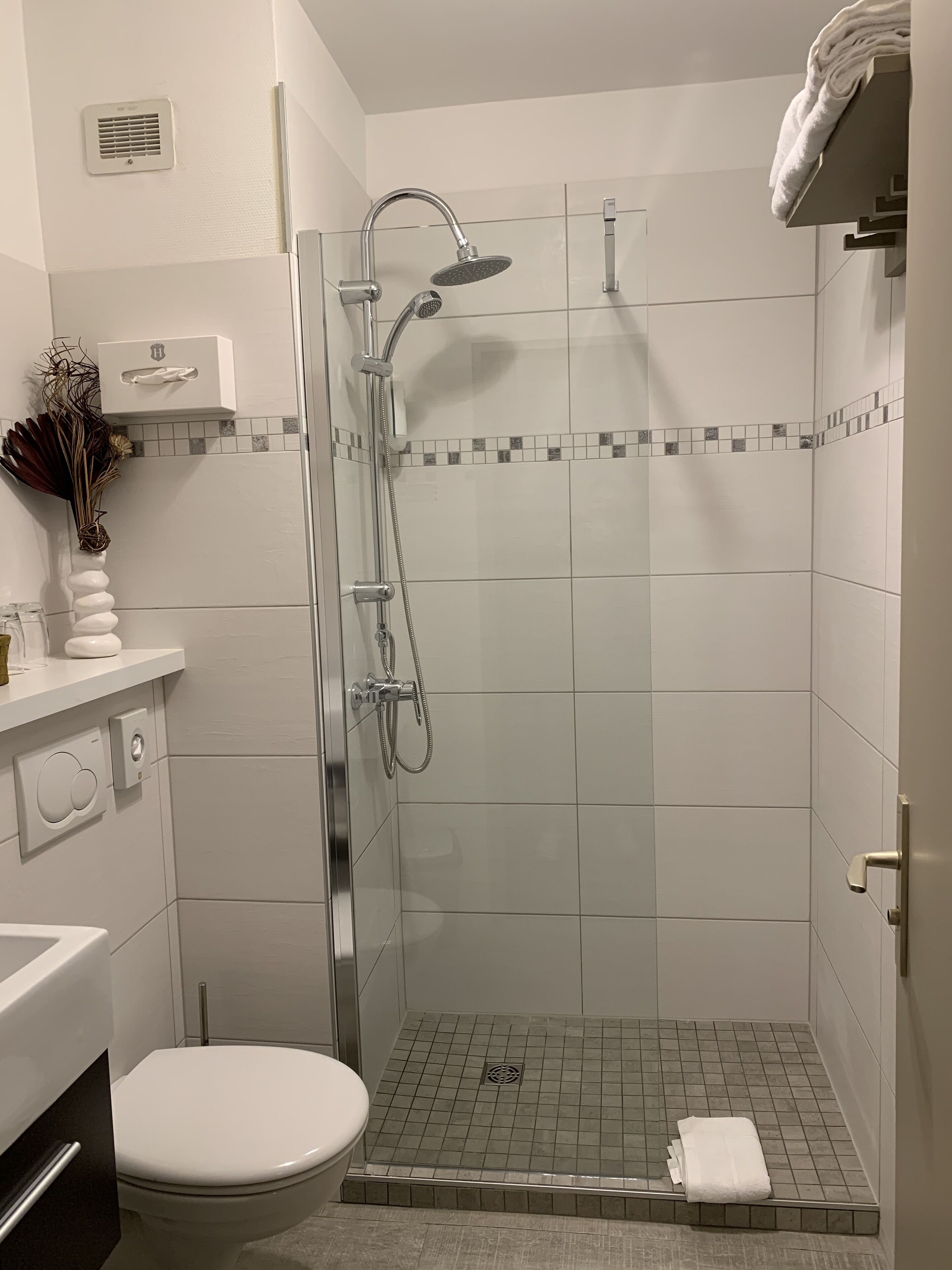 A shower with a handheld showerhead and a wall-mounted faucet.