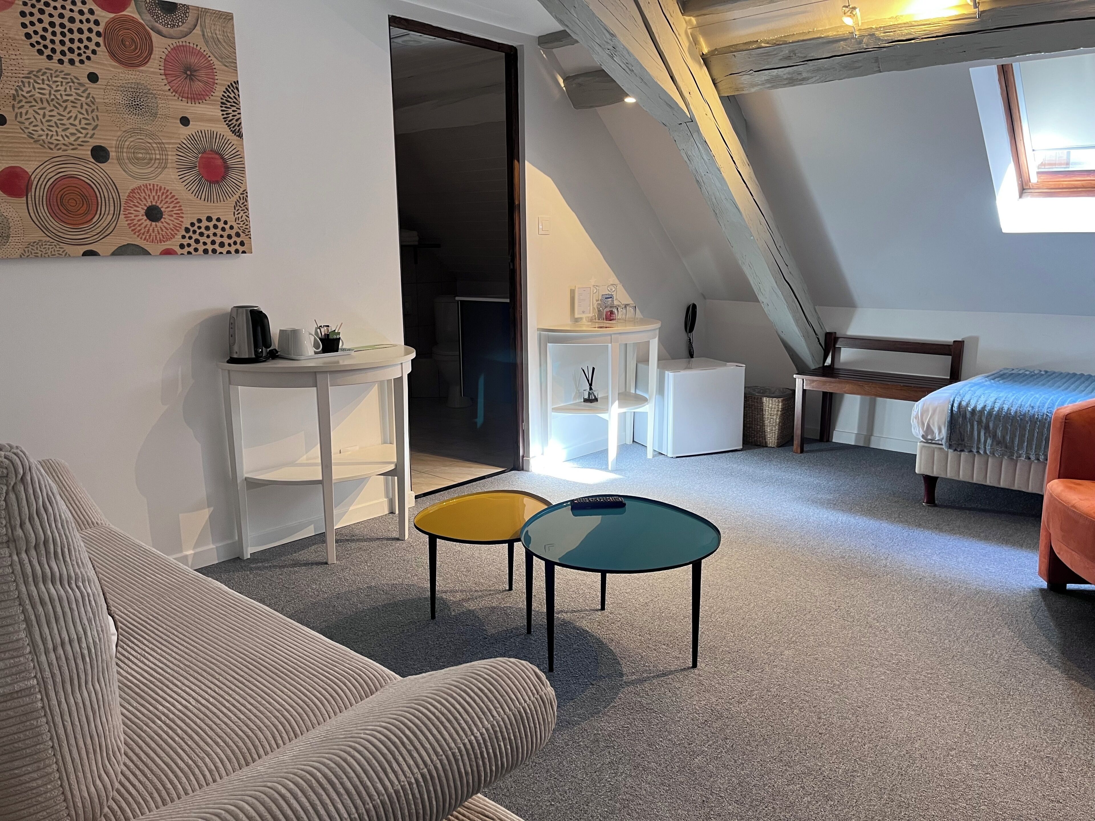 Un dormitorio estilo loft moderno con techo inclinado, una cama, un sofá, una mesita y una silla.