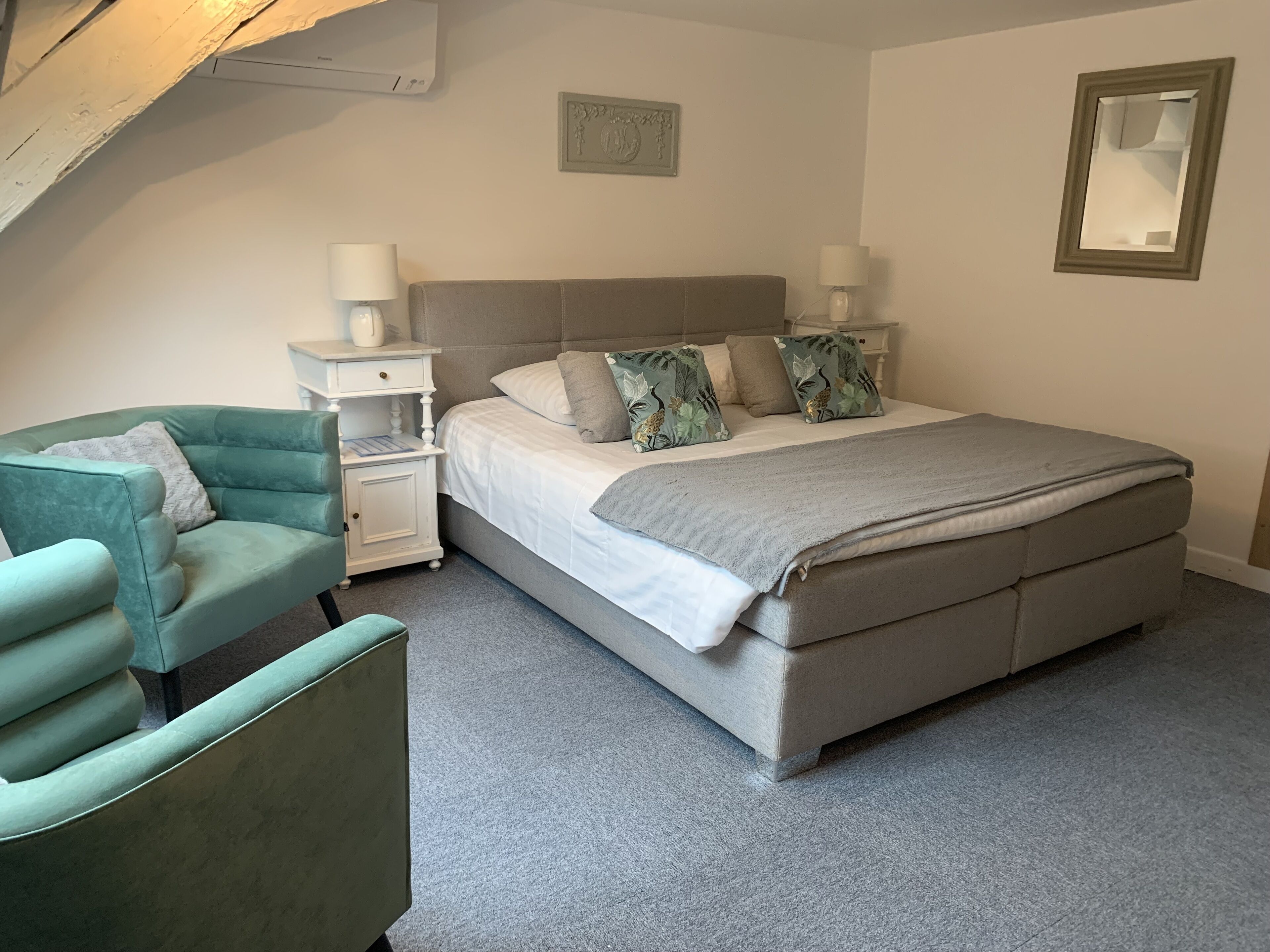 A bedroom with a bed, nightstands, a chair, and a picture frame on the wall.