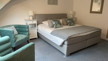 A bedroom with a bed, nightstands, a chair, and a picture frame on the wall.