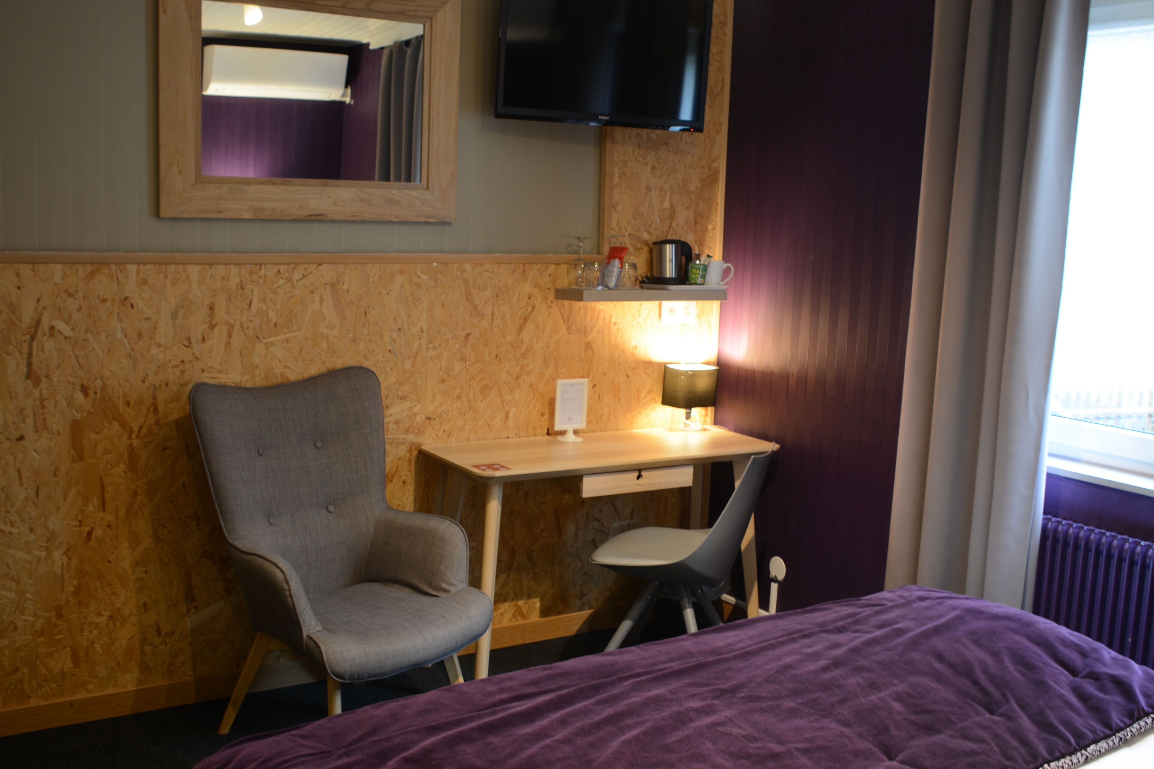 Een hotelkamer met een bed, een bureau, een stoel, een televisie en een raam.