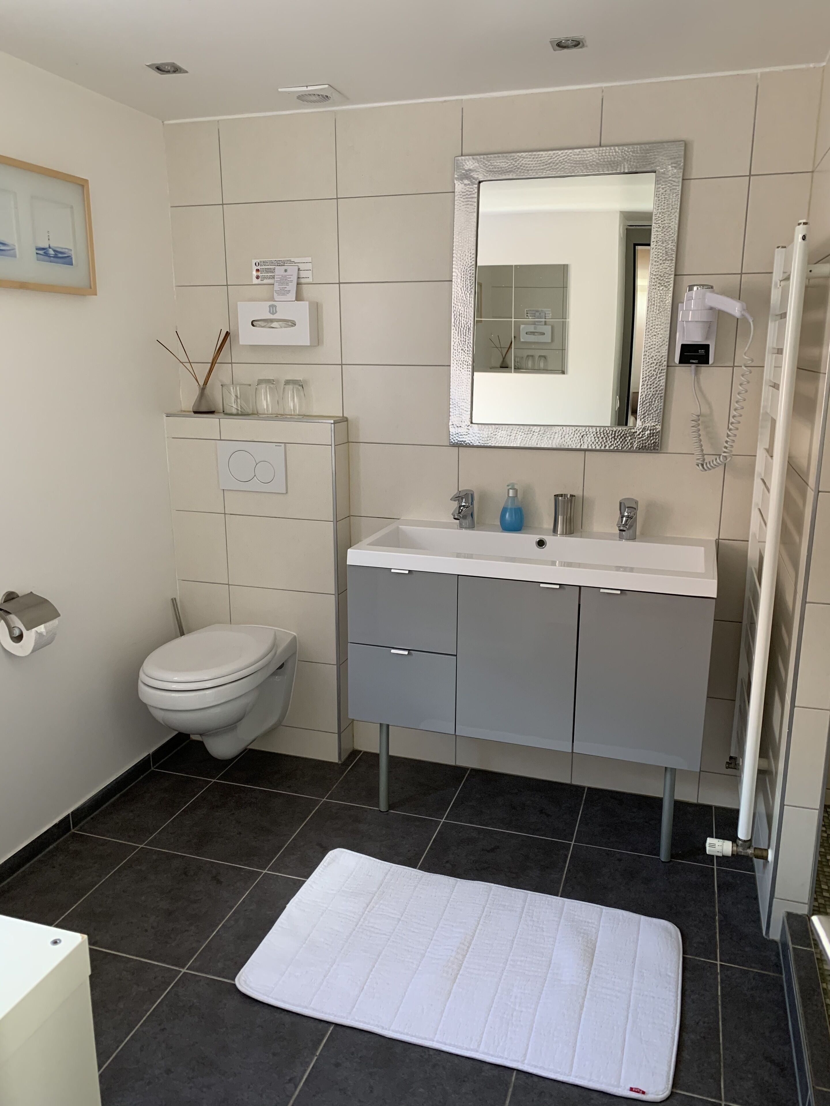 Un baño moderno con inodoro, lavamanos y espejo.
