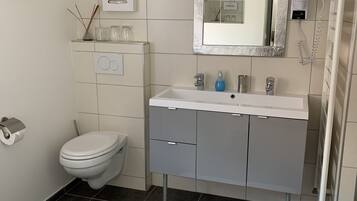 Un baño moderno con inodoro, lavamanos y espejo.