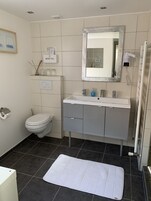Un baño moderno con inodoro, lavamanos y espejo.