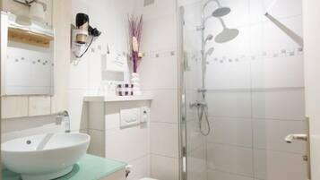 A modern bathroom with a glass-enclosed shower, a white sink, and a toilet.