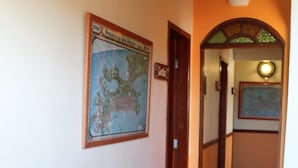A hallway with a tiled floor, a door, and a wall-mounted map. - Rota de Geribá Suítes (Búzios)