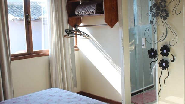 A bedroom with a bed, a wardrobe, a window, and a staircase. - Rota de Geribá Suítes (Búzios)