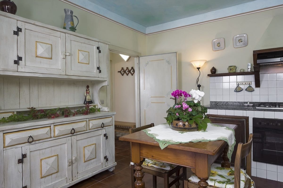 A kitchen with a wooden table, cabinets, and a stove.