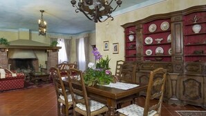 A dining area with a wooden table and chairs, a chandelier, a fireplace, and a china cabinet with dishes. - Bosco Lazzeroni Residence (Montaione)