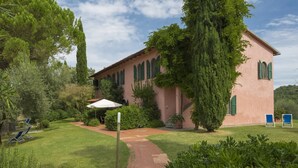 A pink building with a garden, a pathway, and a blue chair. - Bosco Lazzeroni Residence (Montaione)