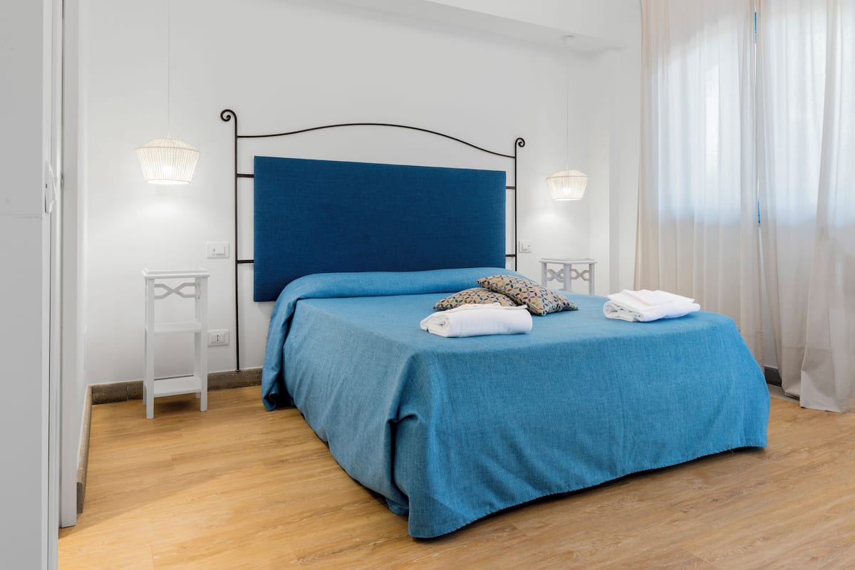 Een slaapkamer met een blauw beddegoed, een witte nachtkastje en een nachtkastje.