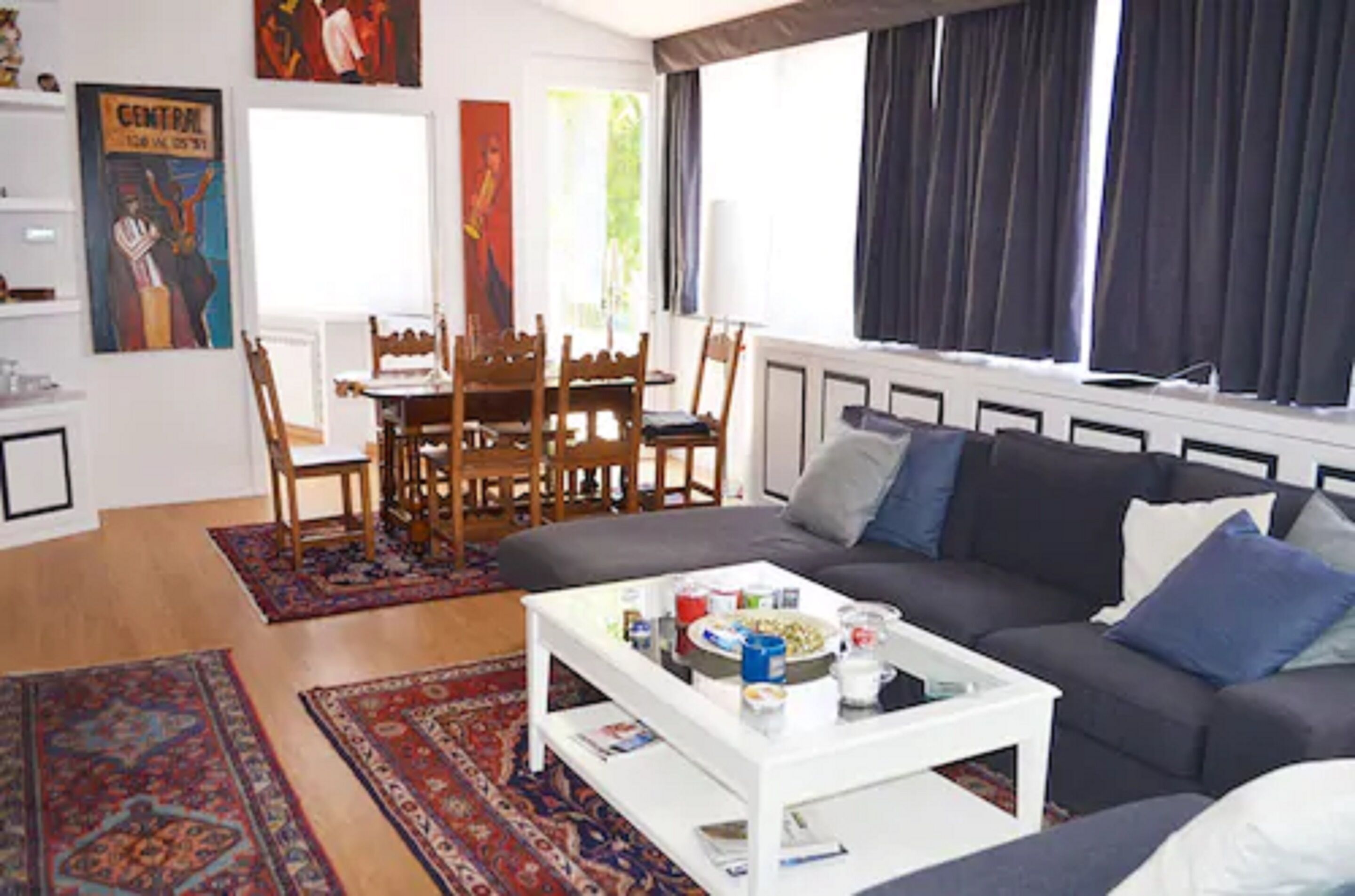 Una sala de estar con sofá, mesa de centro y un comedor con sillas y una mesa.