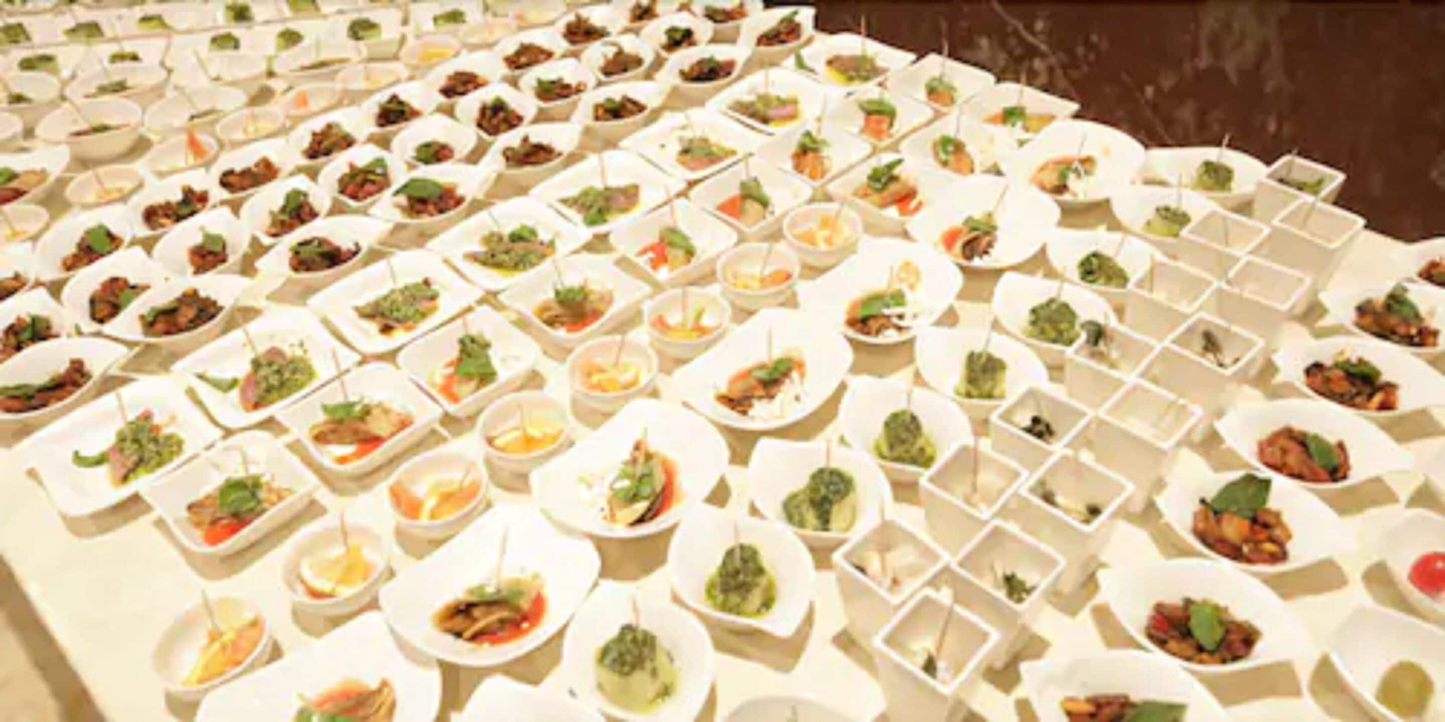 Un buffet con diversi piatti disposti in ciotole bianche.
