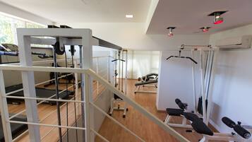 Een sportschool met trainingsapparatuur, een loopband en een halterbank.