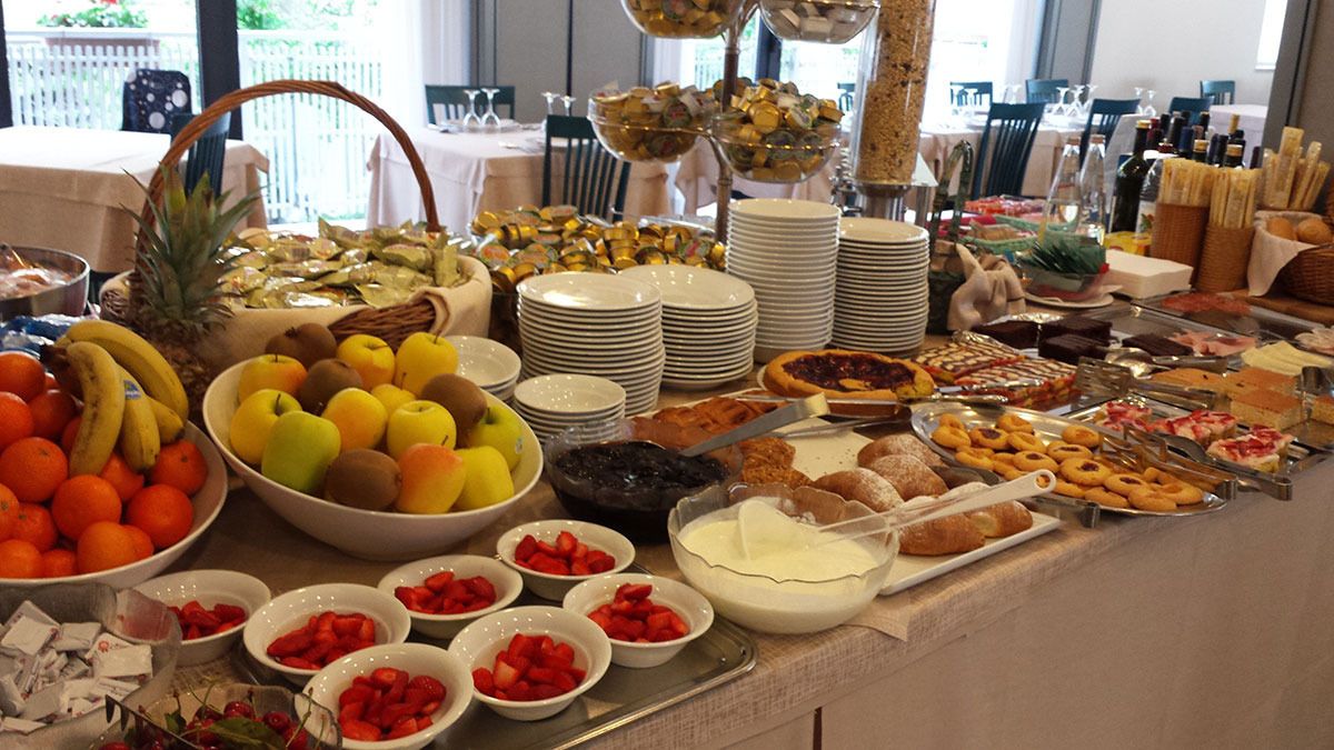 Un bufé con diversas frutas, bollería y postres.