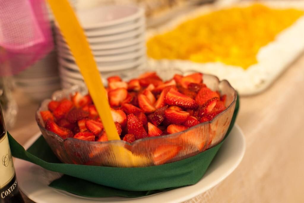 A bowl of sliced strawberries on a plate with a green napkin.